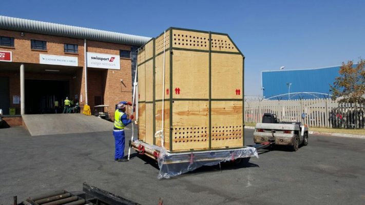 Large airline-approved timber crate being secured on a cargo dolly
